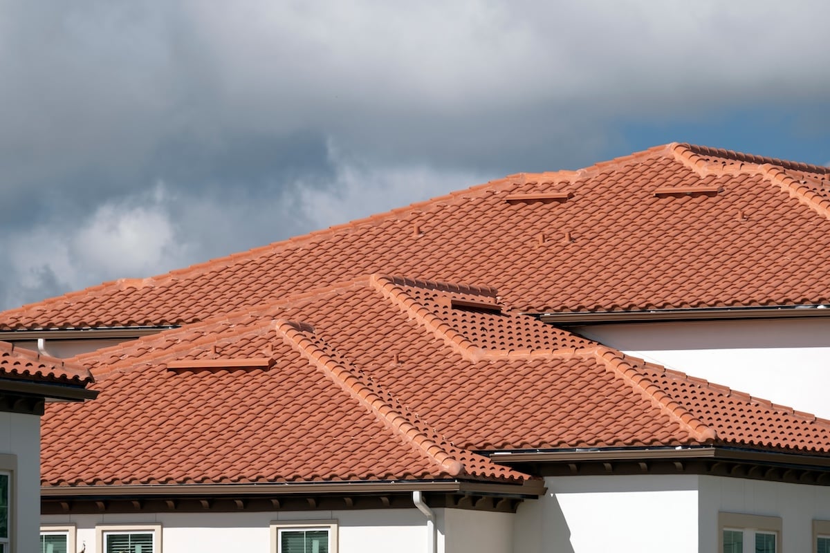 House rooftop covered with yellow ceramic shingles. Tiled covering of residential apartment building.
