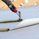 Joiner working on a new house roof making it ready roof tiles or slates roofing tools
