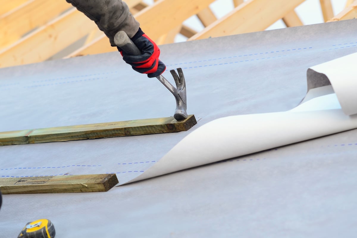 Joiner working on a new house roof making it ready roof tiles or slates roofing tools