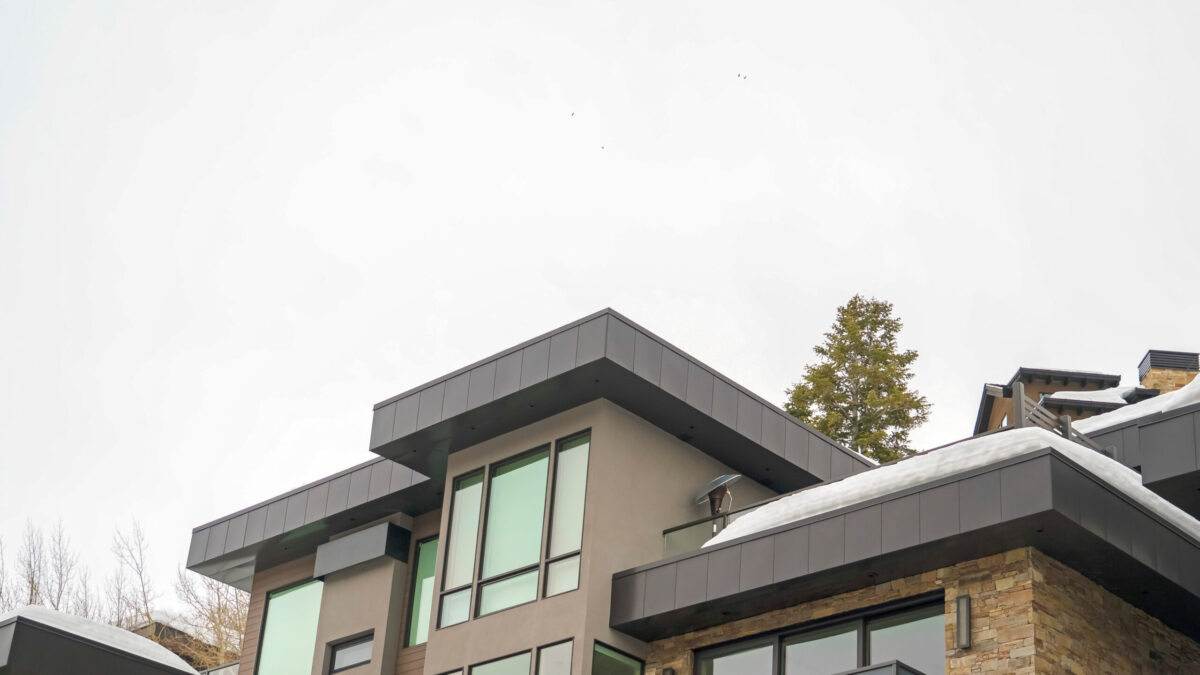 Panorama Modern home exterior with stone wall and flat roof against white sky in winter. The snowy house also features an outdoor stairs and balconies. flat roof replacement