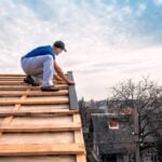 a professional master (roofer) with electric screwdriver covers repairs the roof