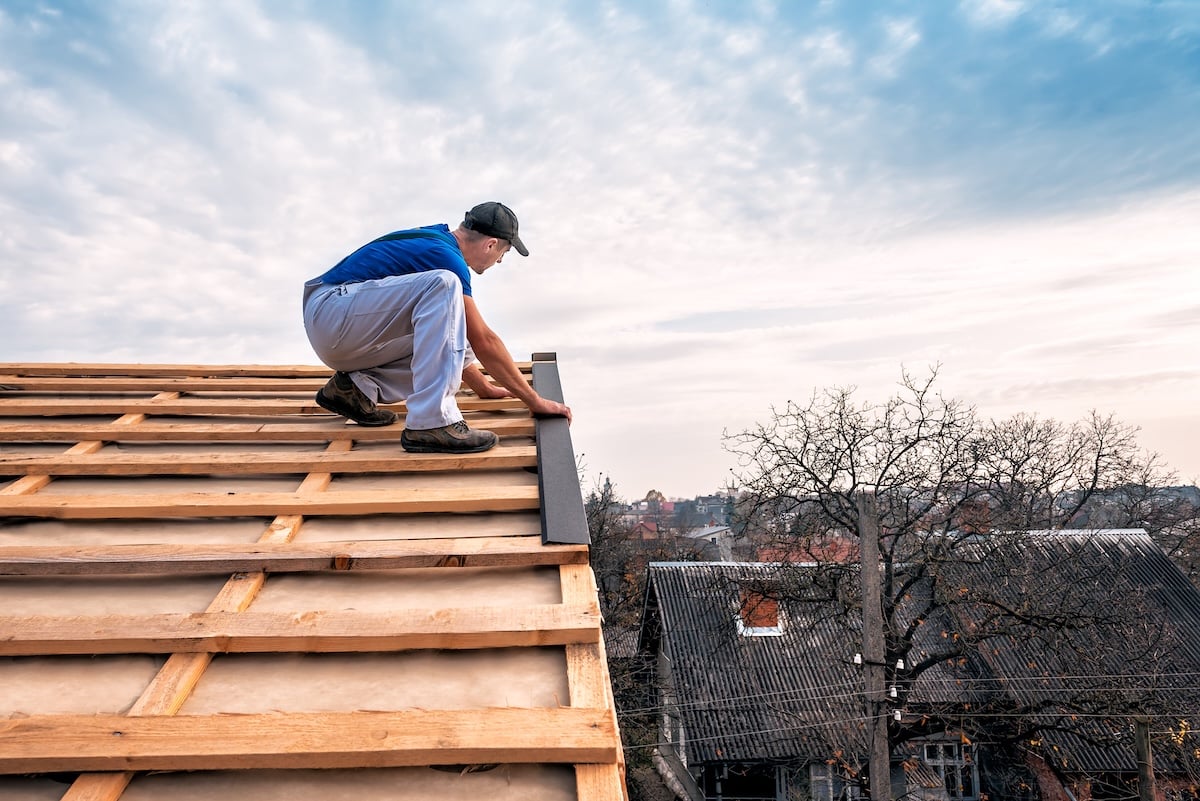a professional master (roofer) with electric screwdriver covers repairs the roof