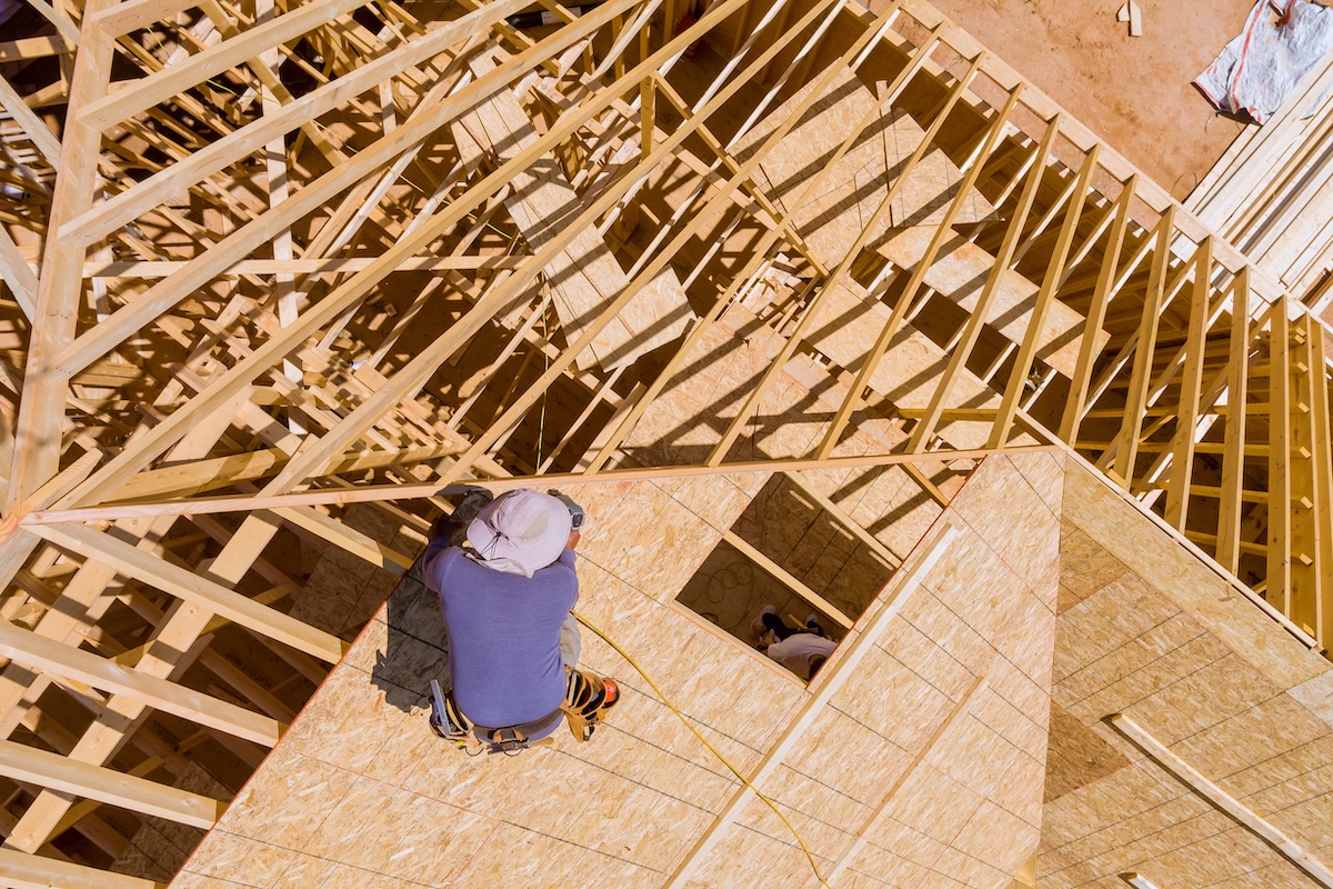 Construction working on the nailing plywood roof sheathing of a new, residential home project an aerial view 