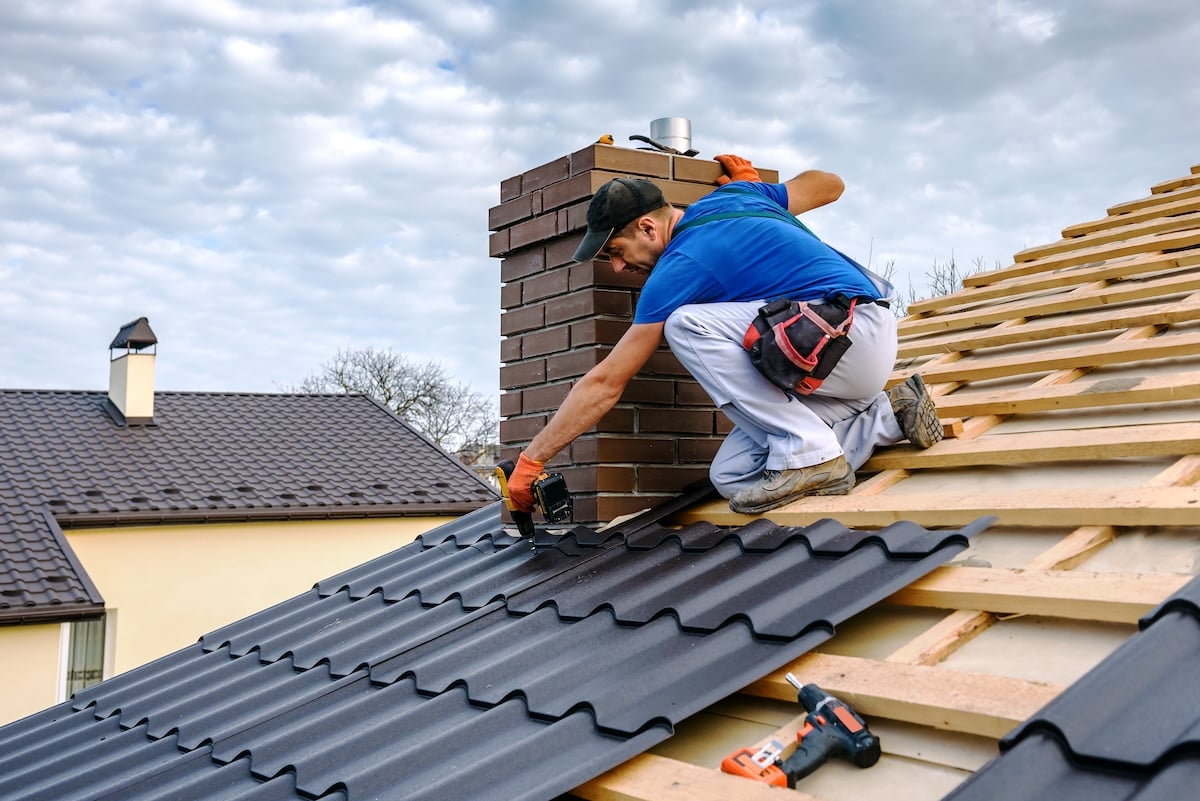 a professional master (roofer) with electric screwdriver covers repairs the roof