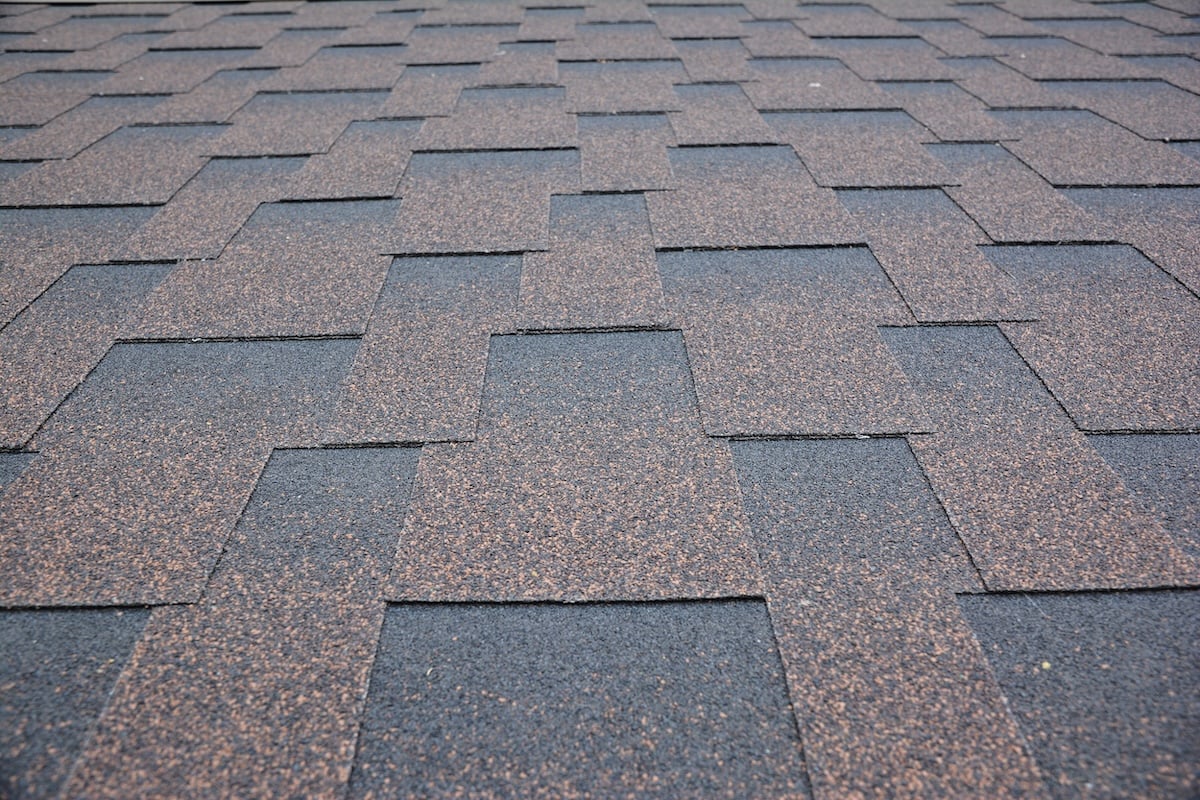 architectural shingles Copper brown roofing asphalt shingles texture background. A close-up of an asphalt laminated, dimensional, or architectural shingled roof. Asphalt shingles roofing construction.