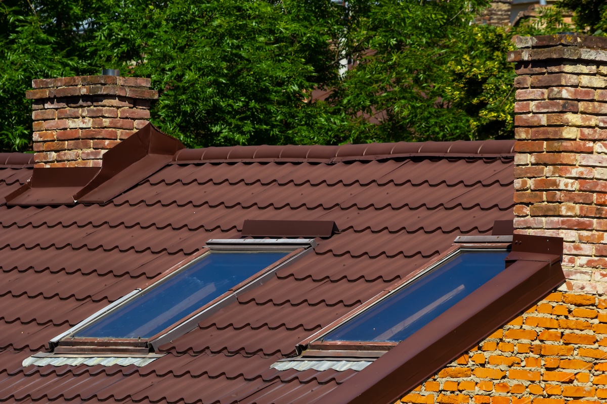 Red house roof with red brick chimney. Ceramic chimney, metal roof tiles, gutters.
