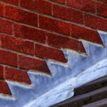 Stepped lead flashing roof gulley creating a water tight seal between roof tiles and brick wall on a domestic house
