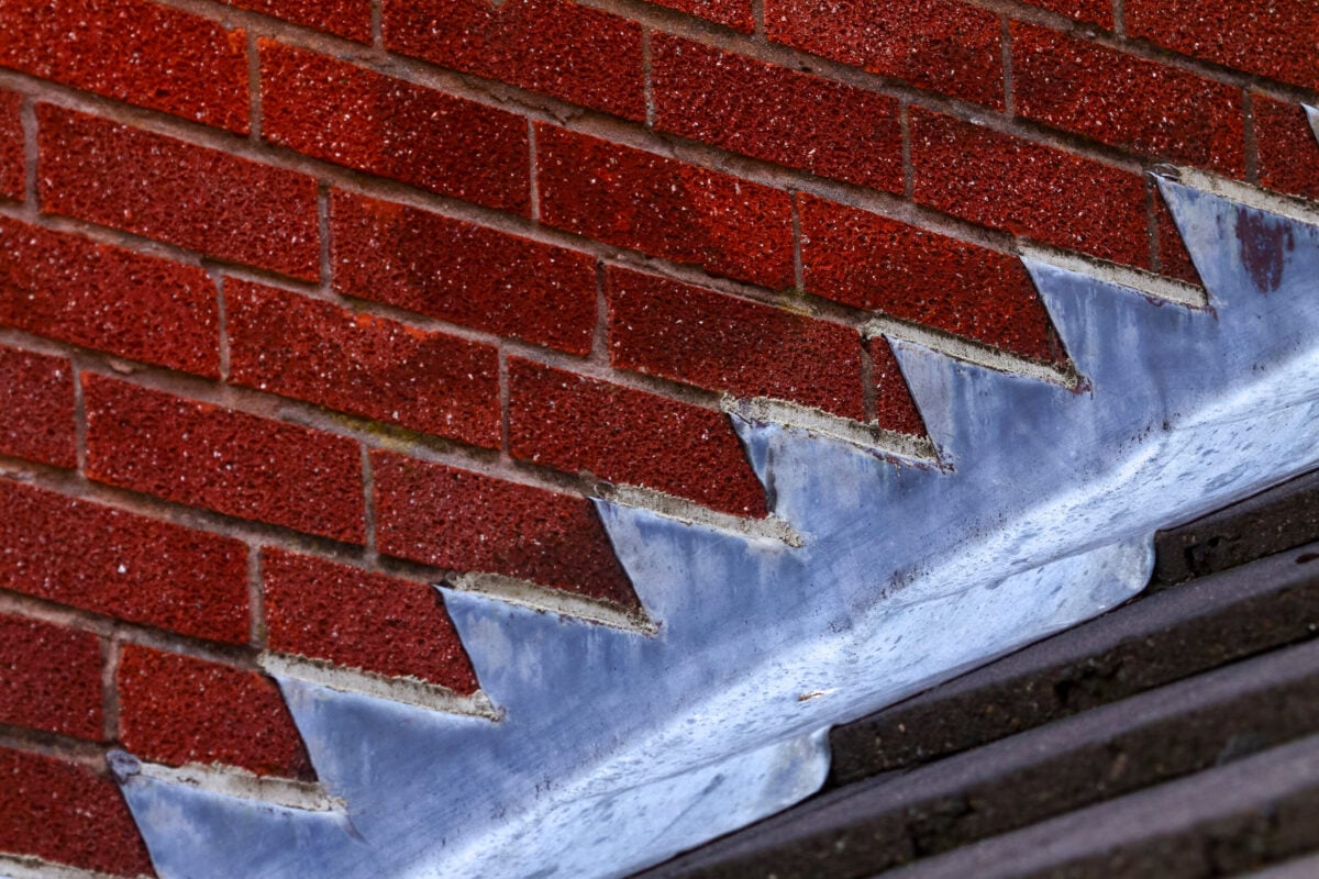 Stepped lead flashing roof gulley creating a water tight seal between roof tiles and brick wall on a domestic house