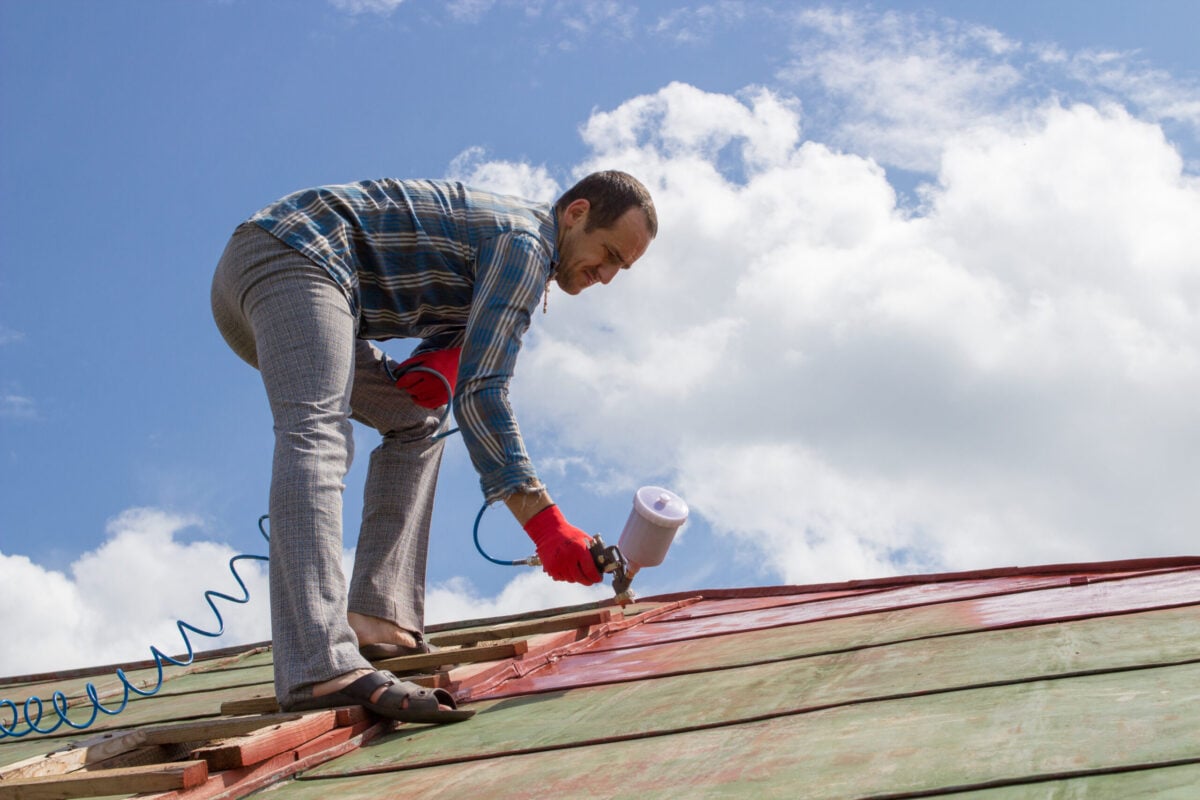can you paint a metal roof A young man paints a roof in the village